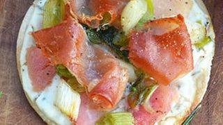 runder Flammkuchen mit speck, Äpfeln, ziegenkäsecreme und frühlingszwiebeln