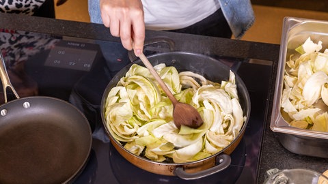 Ilzhöfer kocht für Jordi: Krautfleckerl mit Pilzen und Speck. Die Krautstreifen werden in einen Topf gegeben.