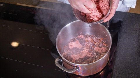 Hackfleisch wird in den Topf gegeben, in dem eine original itlienische Soße entsteht: Ragù alla Bolognese.