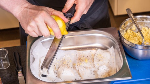 Fischfilet Bordelaise zubereiten: In einem Backblech werden vier Stückchen Fisch mit Pfeffer, Salz und Zitrone gewürzt.