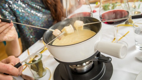 Käsefondue an Silvester: Ein heißer Topf mit flüssigem Käse steht auf dem Tische.