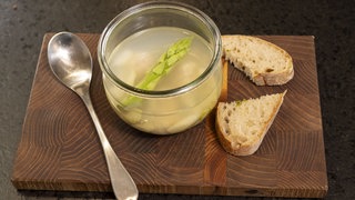 Klare Spargelbrühe mit Quark-Klößchen in einem durchsichtigen Topf
