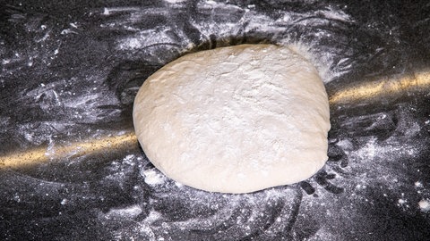 Mit Mehl bestäubter Teigling liegt auf einer Arbeitsfläche: Für den Kassler im Brotteig muss der Hefeteig eine halbe Stunde gehen, so das Rezept von SWR4 Konditor Joachim Habiger.