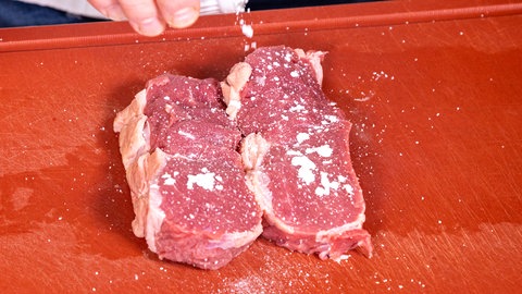 Die Scheiben vom Rind für den Zwiebelrostbraten werden vor dem Anbraten mit etwas Buderzucker besträubt.