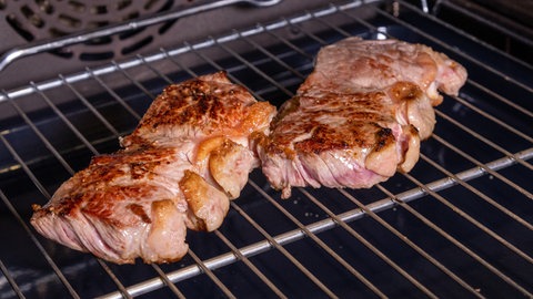 Das Rind braucht Ruhe, denn der saftig und zarte Zwiebelrostbraten liegt auf einem Grillrost im Backofen zum Nachziehen.