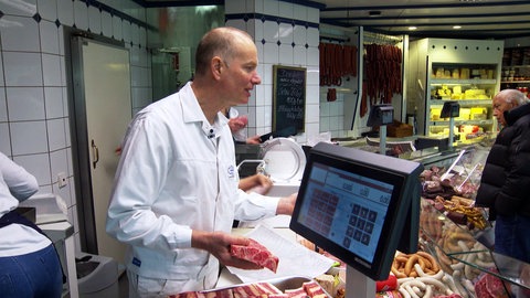 Bernd Glasstetter steht hinter der Fleischtheke seiner Metzgerei in Völkersbach und bedient Kundschaft.