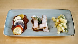 Dry Aged Kotelett vom Sattelschwein mit Ratatouille und Kartoffelwürfeln auf einem Teller