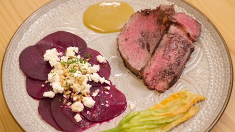 Riderfilet, Carpaccio und eine Zucchiniblüte auf einem Teller