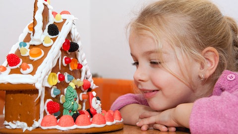 Mädchen schaut auf ein Lebkuchenhaus