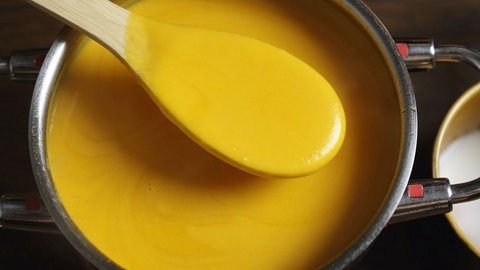 Kürbissuppe im Topf mit Holzlöffel