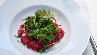 Rote Bete Risotto mit Salat auf einem Teller