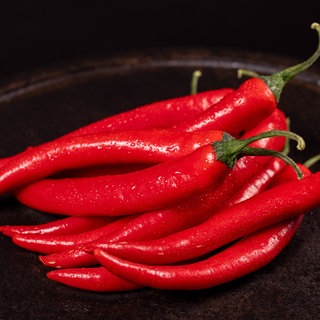 Eine Schala voller Chilis. Möglicherweise könnte ein Wirkstoff aus Chilis gegen Schärfe im Essen helfen.