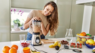 Frau püriert Obst mit Standmixer