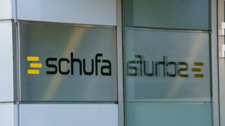 An einem Gebäudeeingang zur Auskunftei Schufa ist der Schufa Schriftzug und das gelbe Logo zu sehen.
