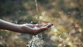 Frau hält Hand unter Wasser