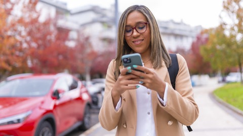 Eine junge Fußgängerin lässt sich im Straßenverkehr von ihrem Smartphone ablenken.