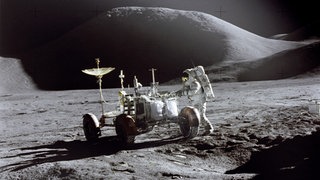 Der US-Astronaut James B. Irwin steht Ende Juli 1971, während der Apollo 15 Mission, auf dem Mond neben einem Mondfahrzeug.