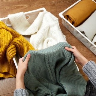Frau sortiert Wollpullover