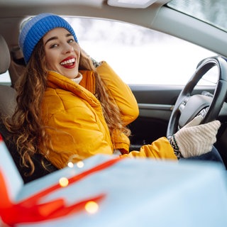 Frau sitzt im Auto mit Geschenken