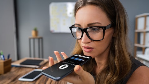 Frau spricht in ihr Handy mit einem Sprachassistenten