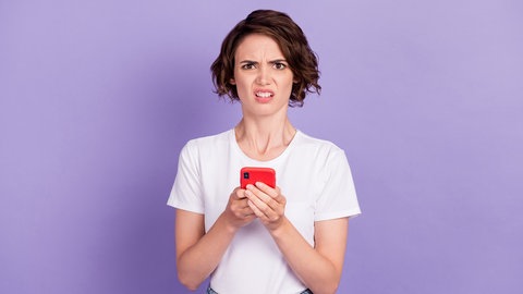 Eine Frau schaut irritiert von ihrem Smartphone auf