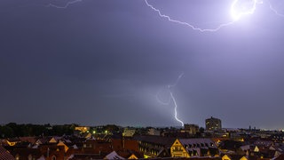 Gewitter mit Blitzen über Häuserdächern | Bei Gewitter und Blitzen: So schützt ihr eure elektronischen Geräte