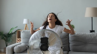 Frau sitzt vor einem Ventilator