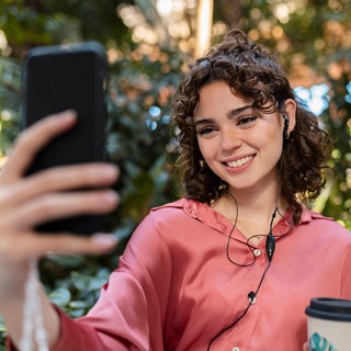 Junge Frau telefoniert mit einem Smartphone: Lauschen Apps wie Instagram, Facebook, Tiktok mit, wenn wir telefonieren - sodaß wir personalisierte Werbung bekommen? 