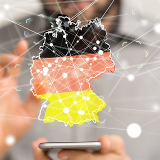 Mann vergrößert digitale Deutschlandkarte, in der sich viele Punkte vernetzen, in der Luft