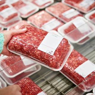 Man sieht eine Hand, die abgepacktes Fleisch hält. Können unterbrochene Kühlketten und zu warme Kühlschränke die Haltbarkeit von Fleisch und Fisch gefährden? Laboranalysen zeigen, ab wann die Qualität der Frischeprodukte beeinflusst wird. 