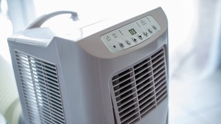  Symbolbild einer mobilen Klimaanlage in einer Wohnung, am Arbeitsplatz oder im Homeoffice.