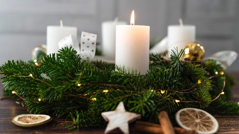 Nachhaltigen Adventskranz basteln: Ein Adventskranz mit weißen Kerzen, getrockneten Orangenscheiben und Zimtstangen