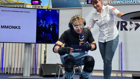 Maimarkt-Reporter Willi Glück testet einen Alterssimulator auf dem Maimarkt im Gläsernen Studio des SWR