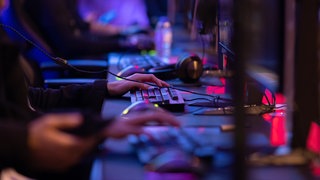 Computer-Mäuse, Headsets und Tastaturen auf einem langen Schreibtisch.