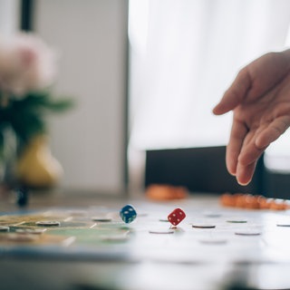 Ein Brettspiel mit Würfeln und Spielfiguren im Hintergrund.