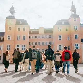 Musiker*innen gehen auf das Schwetzinger Schloss zu