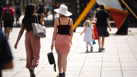 Zwei Frauen laufen bei Sonnenschein durch Stuttgart. 