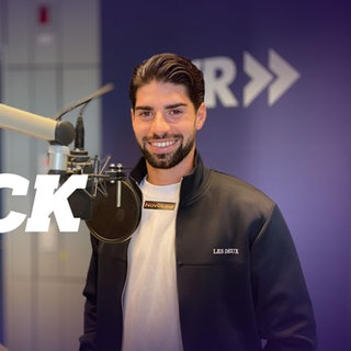 Semih Sahin steht bei seinem Besuch im Nur der FCK Podcast-Studio vor dem Mikrofon. 