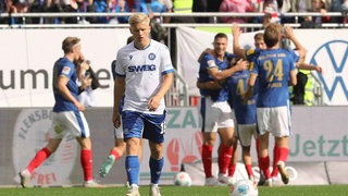 Kiel bejubelt einen Treffer, der Karlsruher Andreas Müller ist bedient