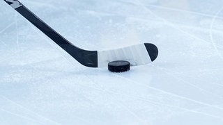 Ein Eishockey-Puck direkt an einem Schläger