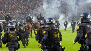 Während des DFB-Pokalspiels zwischen Waldhof Mannheim und dem 1. FC Kaiserslautern kam es zu Ausschreitungen der beiden Fanlager. Die Polizei muss eingreifen und das Feld stürmen.