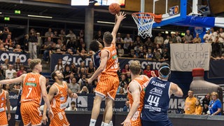 Diego Garavaglia im orangefarbenen Ulmer Trikot versucht, den Korberfolg von Khyri Thomas noch zu verhindern. Der Weißenfelser trifft trotzdem.
