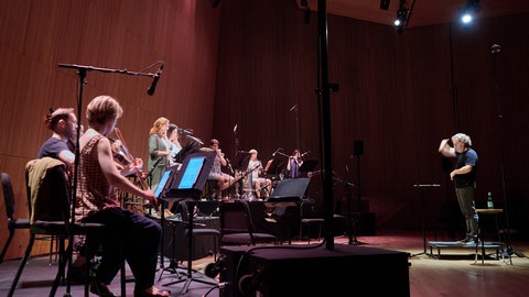 Mehrere Musiker und ein Dirigent proben