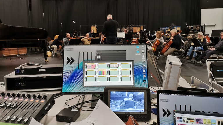 Mann probt ein Ensemble ein Stück mit Computern