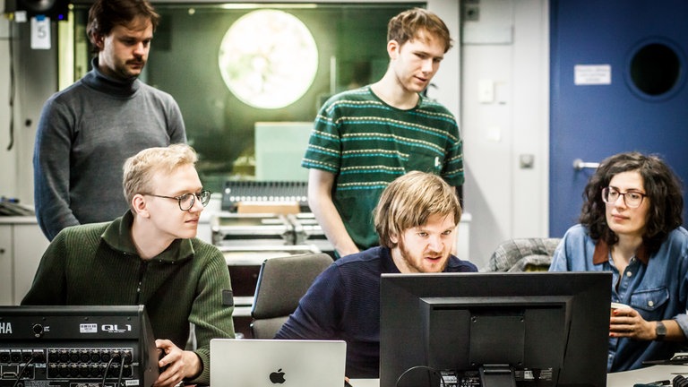 Vier Männer und eine Frau arbeiten konzentriert am Computer