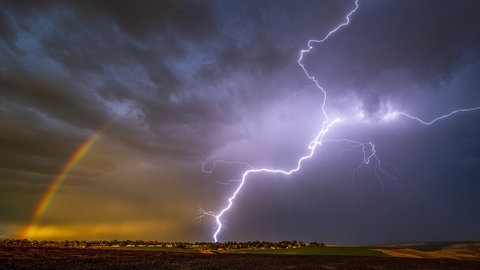Dunkle Gewitterwolken mit Blitz und Regenbogen | So verhaltet ihr euch bei Gewitter, Starkregen und Hagel richtig