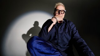 Herbert Grönemeyer stützt seinen Arm auf dem Fuß ab und hat seine Hand vor dem Mund.