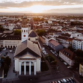 Drohnenaufnahme: Die Innenstadt von Frankenthal mit der Zwölf-Apostel-Kirche bei abendlicher Stimmung.