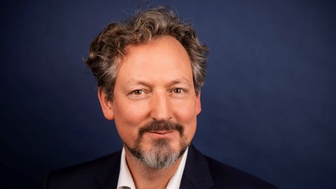 Arzt und Fernsehmoderator Eckart von Hirschhausen lächelt verschmitzt in die Kamera.