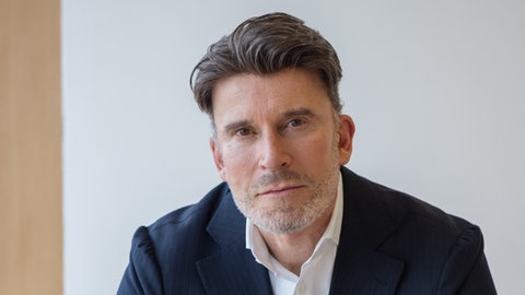 Verhandlungsexperte Thorsten Hofmann schaut in die Kamera. 